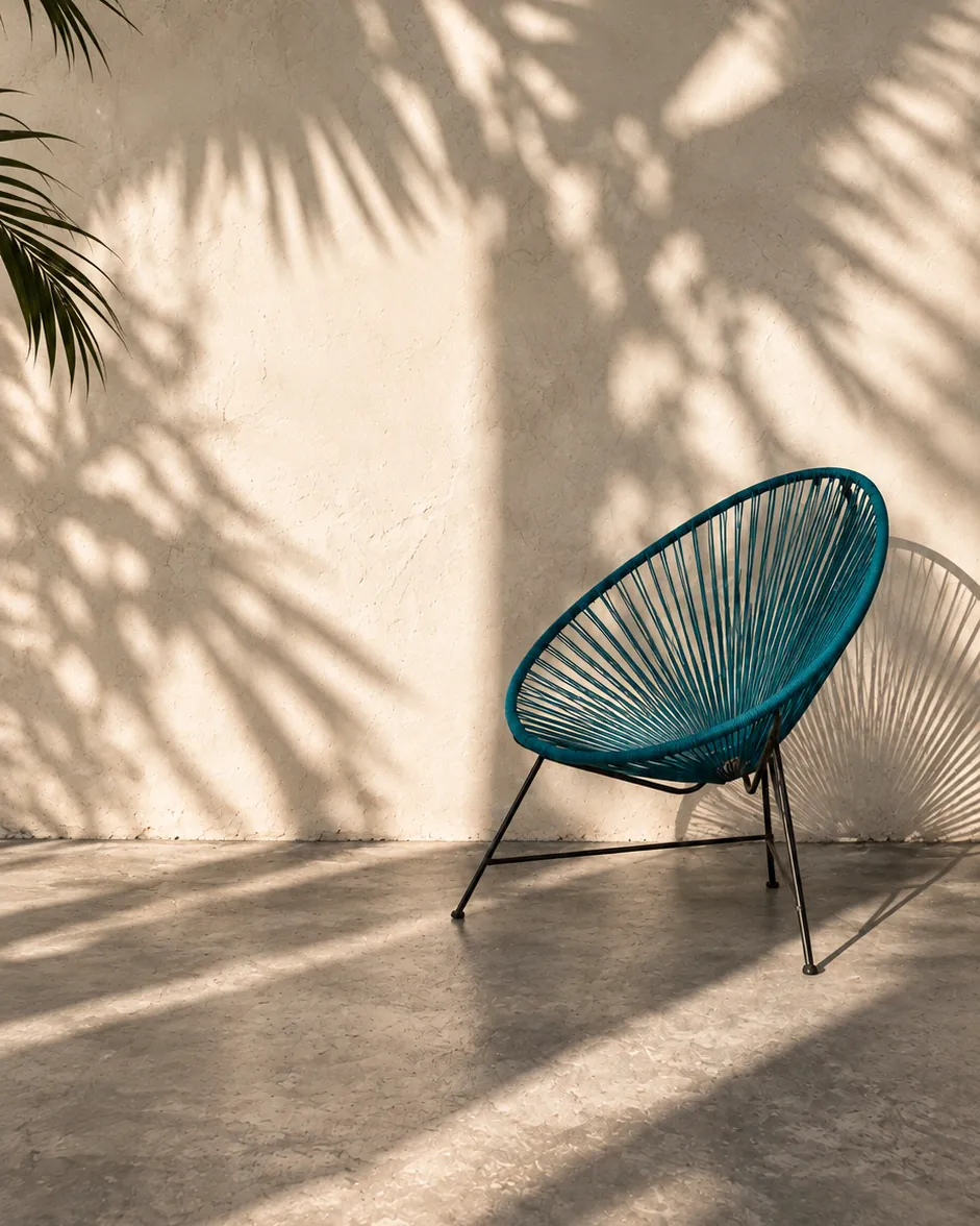Blue Acapulco chair under palm shadows in the Casa Botica patio, Playa del Carmen