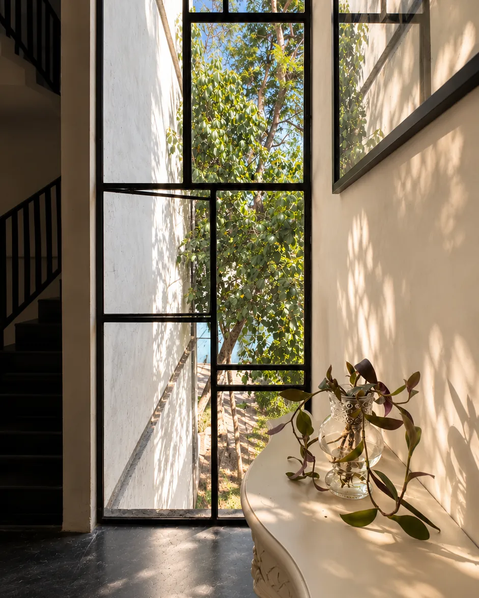 Tall window and a white console in the sunlit entry of Casa Botica spa